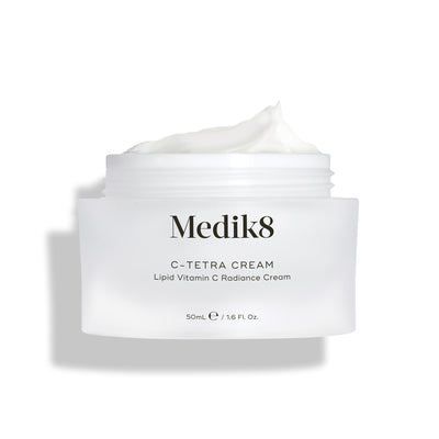 Medik8 C-Tetra Cream jar displayed open against a clean white background with soft shadows. The white, frosted-glass jar features the Medik8 logo and is labeled  C-TETRA CREAM Lipid Vitamin C Radiance Cream  in a 50mL size. A thick swirl of white cream is visible on top of the jar, highlighting its moisturising texture.