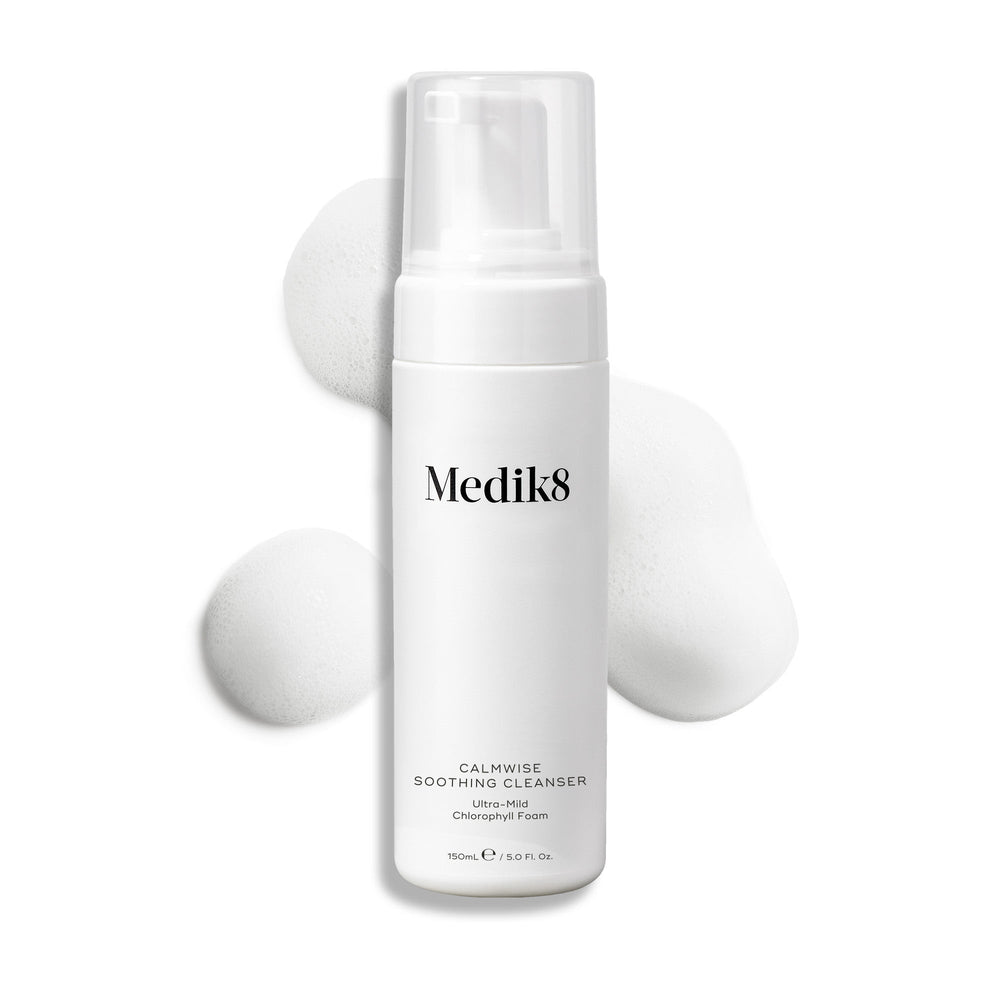 Medik8 Calmwise Soothing Cleanser pump bottle displayed on a white background with a smear of white foam behind it, highlighting the product's texture.