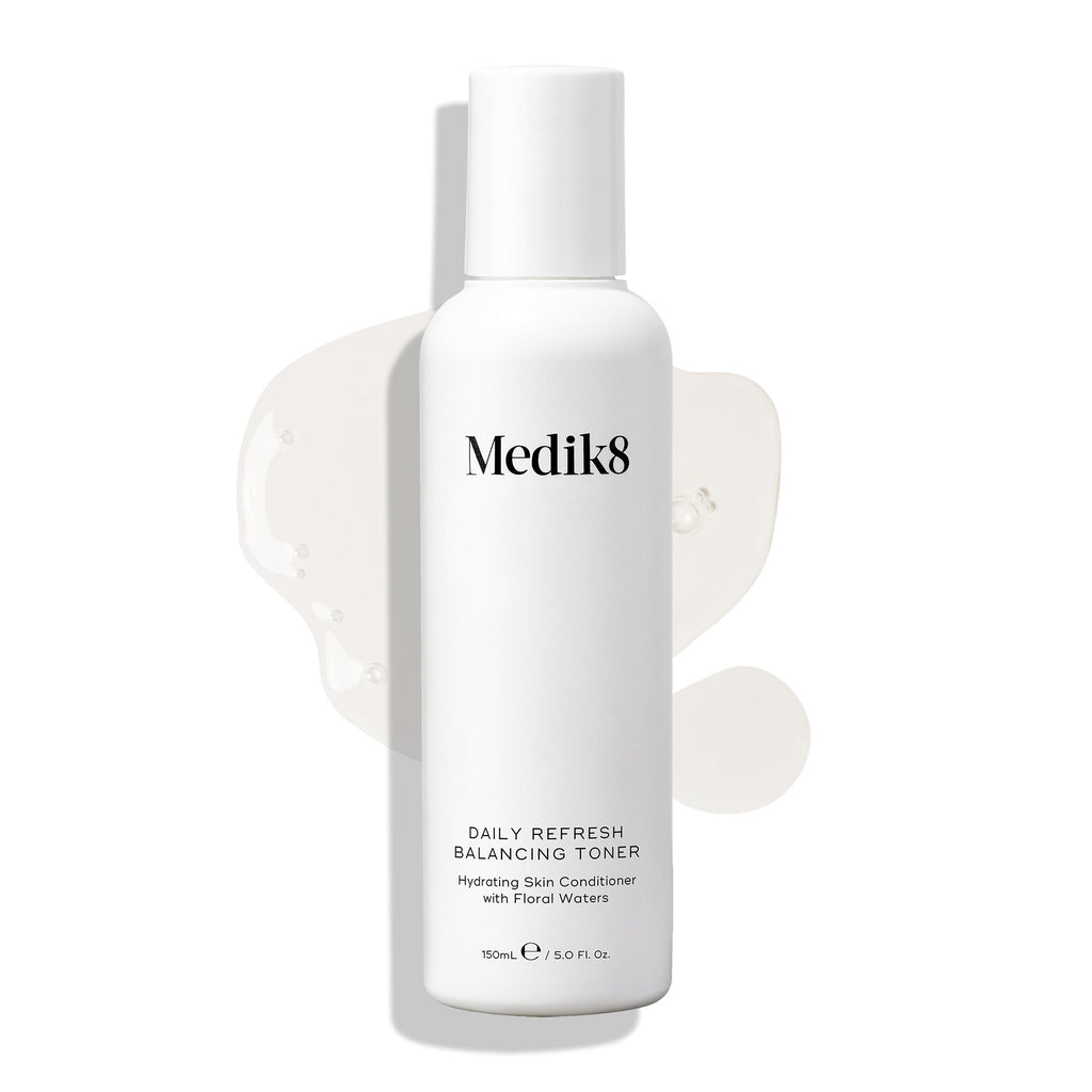 Medik8 Daily Refresh Balancing Toner bottle stands on a white background with a clear liquid spill. Text identifies it as a  Hydrating Skin Conditioner with Floral Waters  in a 150mL size.