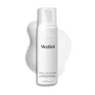 Medik8 Micellar Mousse pump bottle displayed on a white background with a smear of white foam behind it, highlighting the product's texture.