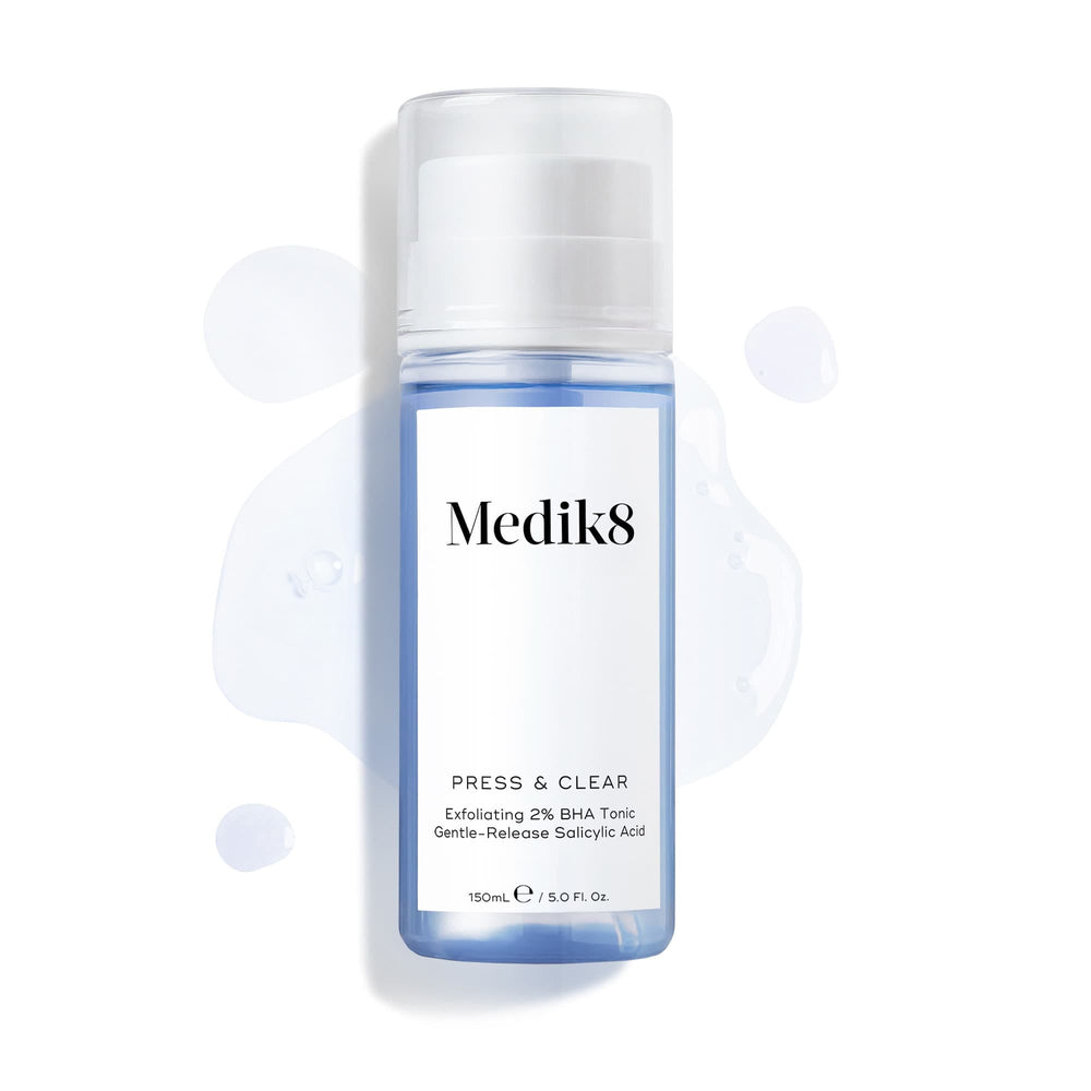 Medik8 Press & Clear bottle (150ml) displayed on a white background with splashes of blue tonic around it. Text highlights the  Exfoliating 2% BHA Tonic  formula.