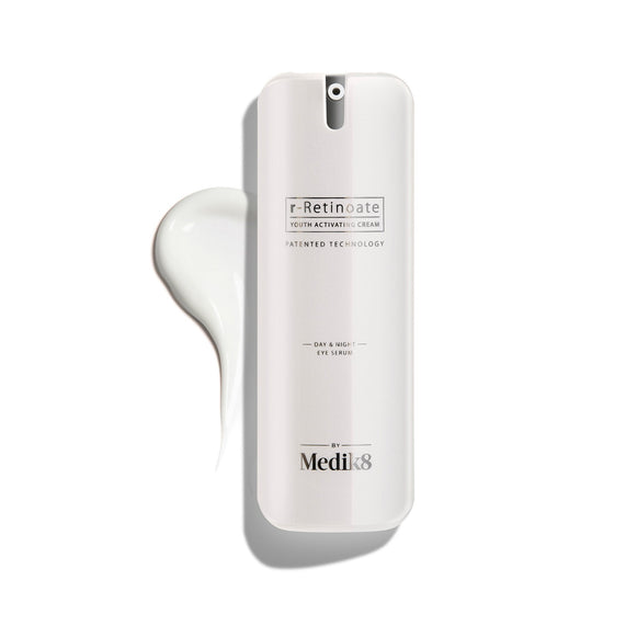 A white pump bottle of r-Retinoate Day & Night Eye Serum, with a droplet of product next to it.-49