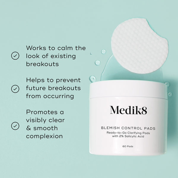 Medik8 Blemish Control Pads jar is shown against a light teal background with a single textured white pad and clear liquid droplets. Text highlights that the product  Works to calm the look of existing breakouts,   Helps to prevent future breakouts from occurring,  and  Promotes a visibly clear & smooth complexion. 