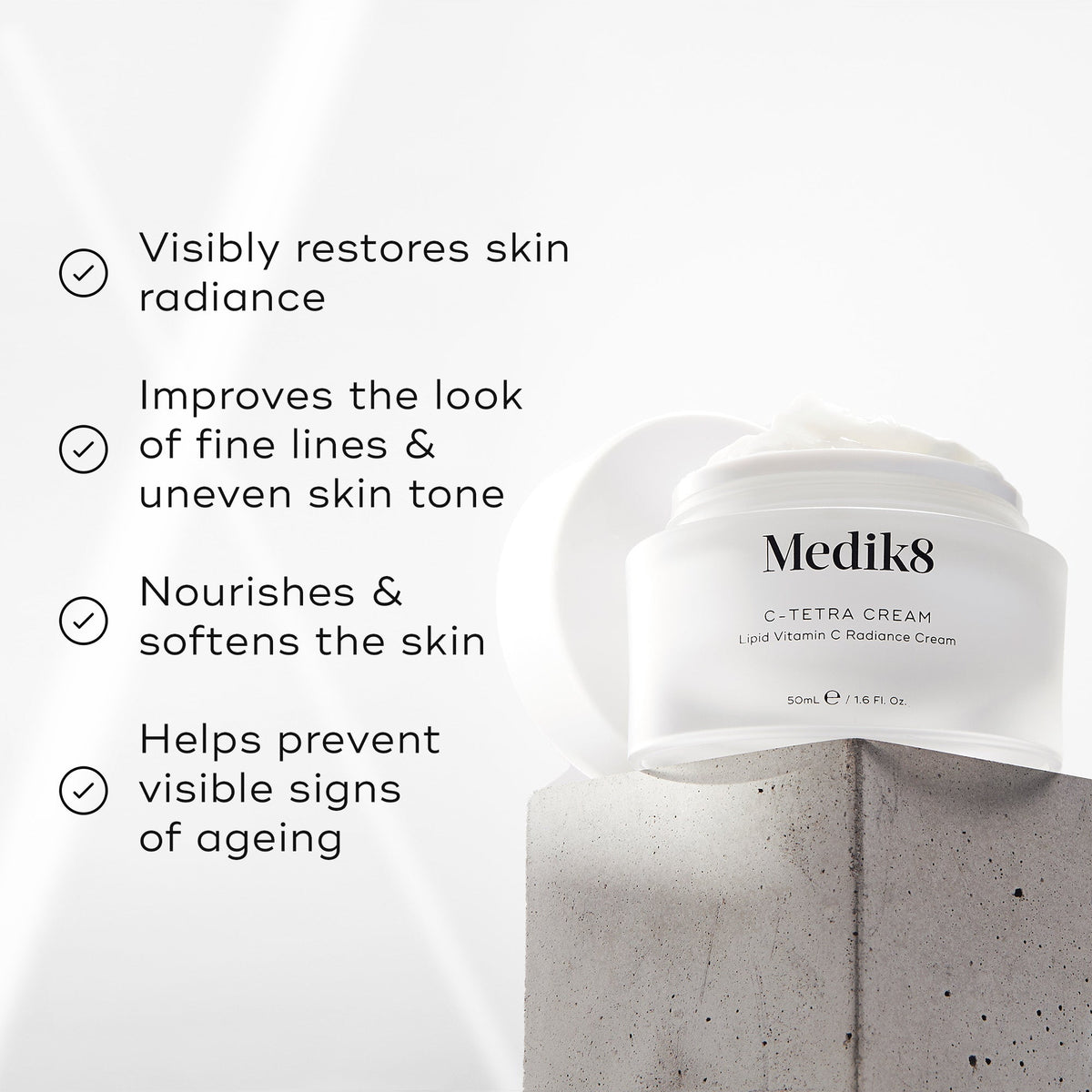 Medik8 C-Tetra Cream jar displayed on a grey stone block against a white background with soft light rays. The image features four check-marked claims:

Visibly restores skin radiance

Improves the look of fine lines & uneven skin tone

Nourishes & softens the skin

Helps prevent visible signs of ageing