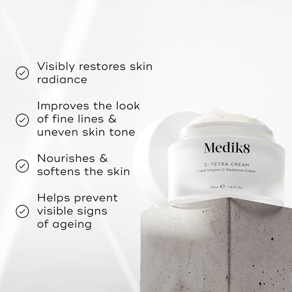 Medik8 C-Tetra Cream jar displayed on a grey stone block against a white background with soft light rays. The image features four check-marked claims:

Visibly restores skin radiance

Improves the look of fine lines & uneven skin tone

Nourishes & softens the skin

Helps prevent visible signs of ageing