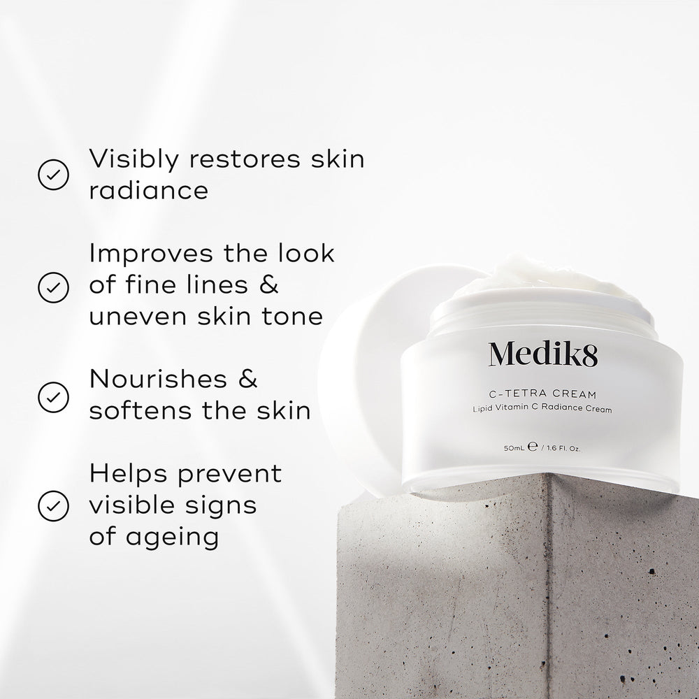 "Medik8 C-Tetra Cream jar displayed on a grey stone block against a white background with soft light rays. The image features four check-marked claims:

Visibly restores skin radiance

Improves the look of fine lines & uneven skin tone

Nourishes & softens the skin

Helps prevent visible signs of ageing"