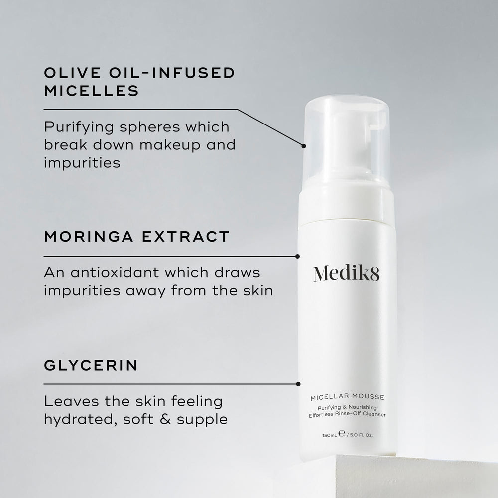A Medik8 Micellar Mousse bottle displayed on a white block. Lines connect the bottle to text explaining key ingredients:  Olive Oil-Infused Micelles  to break down makeup,  Moringa Extract  to draw out impurities, and  Glycerin  for hydration.