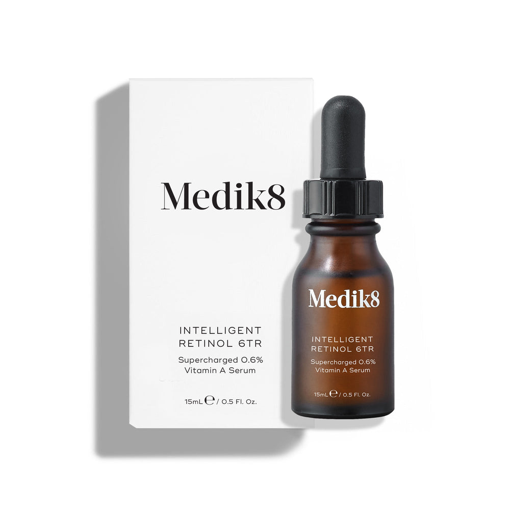 Medik8 Intelligent Retinol 6TR serum bottle stands in front of its matching white product carton on a clean white background. Text identifies the product as a 15mL  Supercharged 0.6% Vitamin A Serum. 