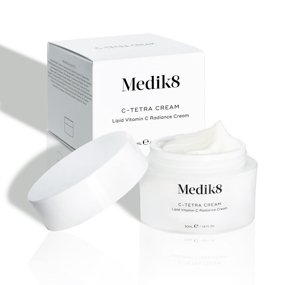 Medik8 C-Tetra Cream jar and its white cardboard carton displayed on a clean white background with soft shadows. The open white, frosted-glass jar features the Medik8 logo and is labeled  C-TETRA CREAM Lipid Vitamin C Radiance Cream  in a 50mL size. A thick swirl of white cream is visible on top of the jar, with the white box behind it showing the product name and a partial ingredients list.