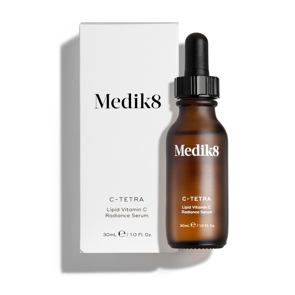 Medik8 C-Tetra Luxe serum bottle and its white cardboard carton displayed on a clean white background with soft shadows. The amber glass bottle and white box both feature the Medik8 logo and identify the product as  C-TETRA LUXE Lipid Vitamin C Enhanced Radiance Serum  in a 30mL size.