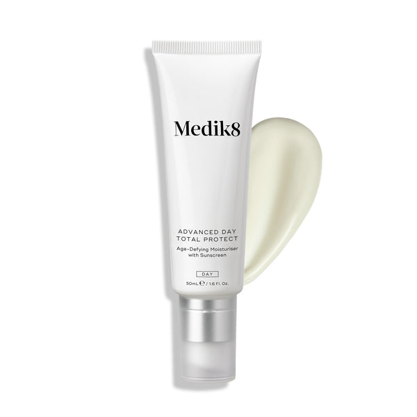 Medik8 Advanced Day Total Protect tube stands against a clean white background with a large, creamy white moisturizer smear. Text identifies the product as an Age-Defying Moisturiser with SPF 30 and 5* UVA protection in a 50mL size.