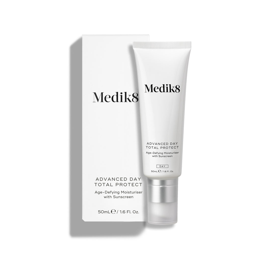 Medik8 Advanced Day Total Protect tube stands on a clean white background with a matching white outer carton. Text identifies the product as a 50mL Age-Defying Moisturiser with SPF 30 and 5* UVA protection.