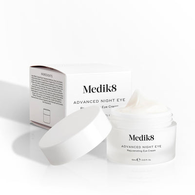 Medik8 Advanced Night Eye cream jar sits open next to its packaging box on a white background. Text highlights the  Rejuvenating Eye Cream  formula and 15mL size.