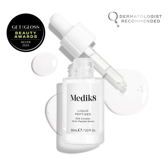 A clear glass dropper bottle of Liquid Peptides serum is presented, with its dropper removed and resting beside it and serum droplets, showing the texture-8