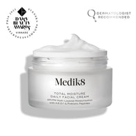 An open frosted glass jar of Medik8 Total Moisture Daily Facial Cream with a peak of white cream on top, set against a clean white background. Badges in the top corners indicate it is a 
