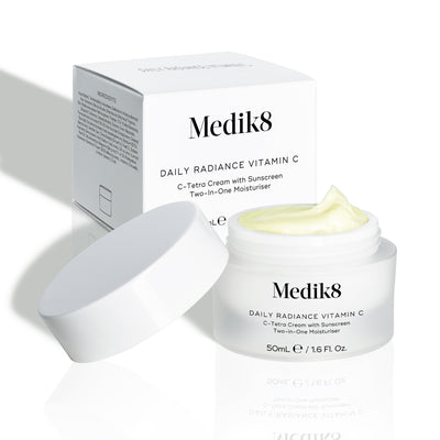 Medik8 Daily Radiance Vitamin C cream jar is shown open with a generous peak of pale yellow cream on top and it's carton packaging on the side. Text identifies the product as a 50mL C-Tetra Cream Two-in-One Moisturiser.