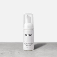 Bottle of Medik8 Clarifying Foam Refreshing AHA/BHA Blemish Cleanser stands against a grey and white background. The 40ml bottle has a clear cap and pump dispenser. 