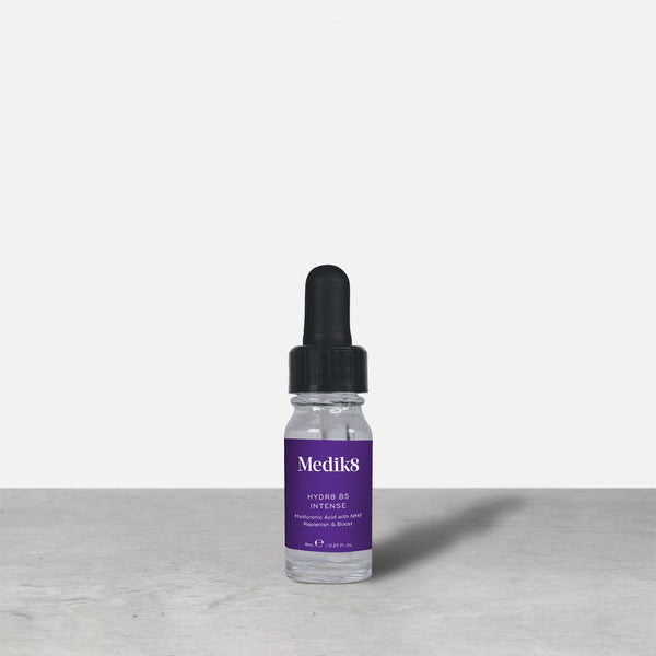 A purple 8ml glass dropper bottle of Medik8 HYDR8 B5 INTENSE serum stands next to its white packaging box on a grey surface against a white background. Text on both reads: "Medik8, HYDR8 B5 INTENSE, Hyaluronic Acid with NMF Replenish & Boost, 8mLe / 0.27 Fl. Oz.".