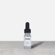 Medik8 Hydr8 B5 travel-sized serum bottle stand on a grey textured surface against a neutral background. Text on the 8mL bottle identifies it as a "Liquid Rehydration Serum.