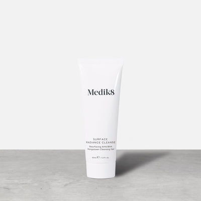 A single white tube of Medik8 Surface Radiance Cleanse stands on a grey surface. Label text includes: Medik8, SURFACE RADIANCE CLEANSE, Resurfacing AHA/BHA, Mangosteen Cleansing Gel, and 40mL℮ / 1.3 Fl. Oz.