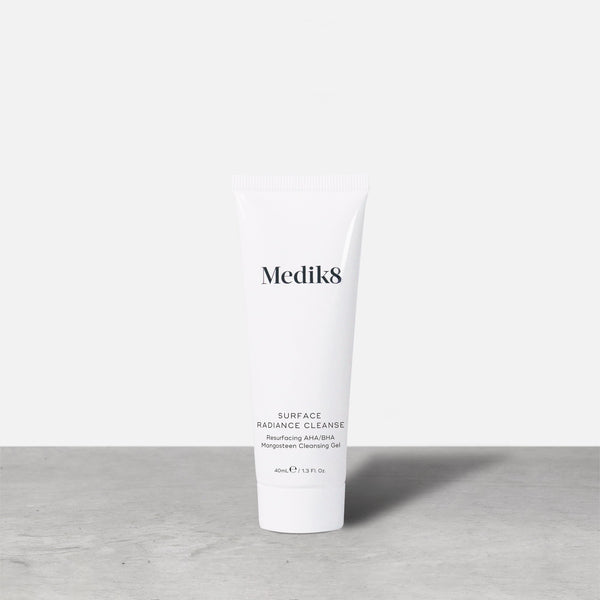 A single white tube of Medik8 Surface Radiance Cleanse stands on a grey surface. Label text includes: Medik8, SURFACE RADIANCE CLEANSE, Resurfacing AHA/BHA, Mangosteen Cleansing Gel, and 40mL℮ / 1.3 Fl. Oz.