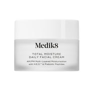 A travel-sized 12.5mL frosted jar of Medik8 Total Moisture Daily Facial Cream standing next to its white cardboard carton. The products are displayed on a textured grey surface against a clean white background. Text on both reads: "AM/PM Multi-Layered Moisturisation with H.E.O.™ & Prebiotic Peptides."