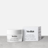 A travel-sized 12.5mL frosted jar of Medik8 Total Moisture Daily Facial Cream standing next to its white cardboard carton. The products are displayed on a textured grey surface against a clean white background. Text on both reads: "AM/PM Multi-Layered Moisturisation with H.E.O.™ & Prebiotic Peptides."